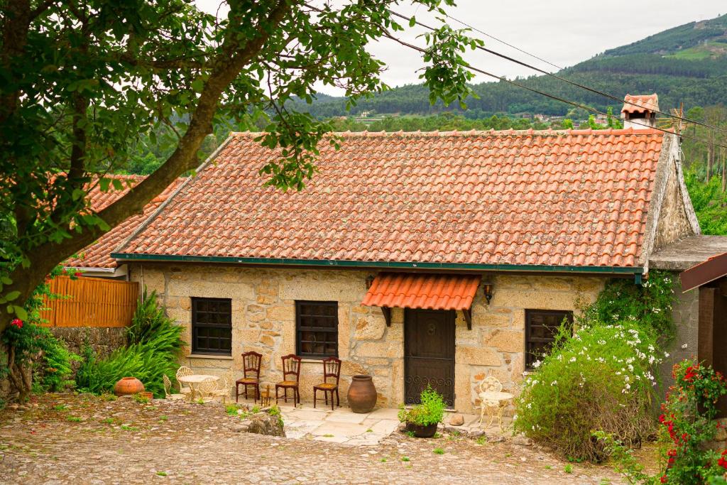 una pequeña casa de piedra con sillas delante en Casa das Infusões - Soalheiro, en Melgaço