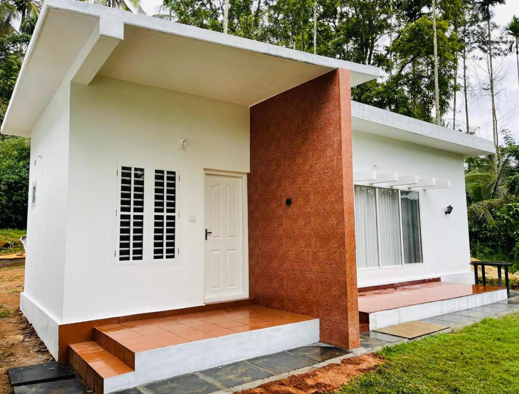 a small white house with a brick wall at Silver Oak By Exuberance Stays (Independent Holiday Home) in Wayanad