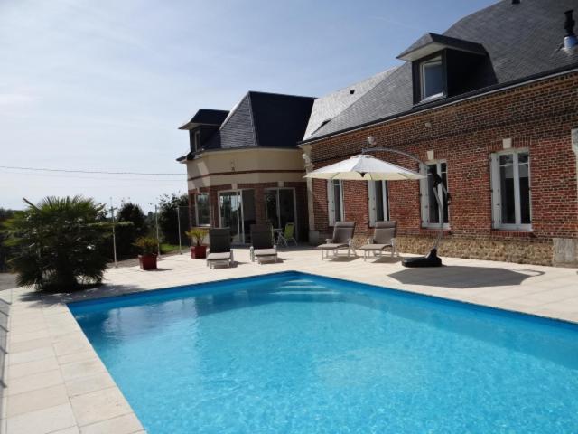 uma grande piscina azul em frente a uma casa em chambres d'hôtes près de FECAMP em Ganzeville