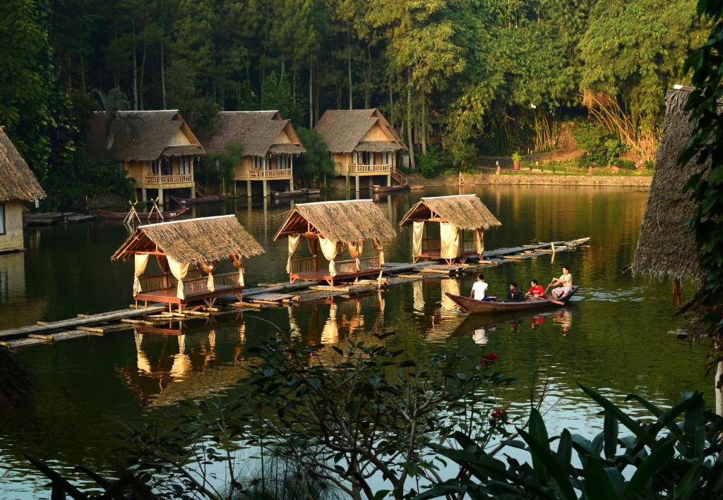 a group of people in a boat on a lake with huts at Kampung Sampireun Resort & Spa in Garut