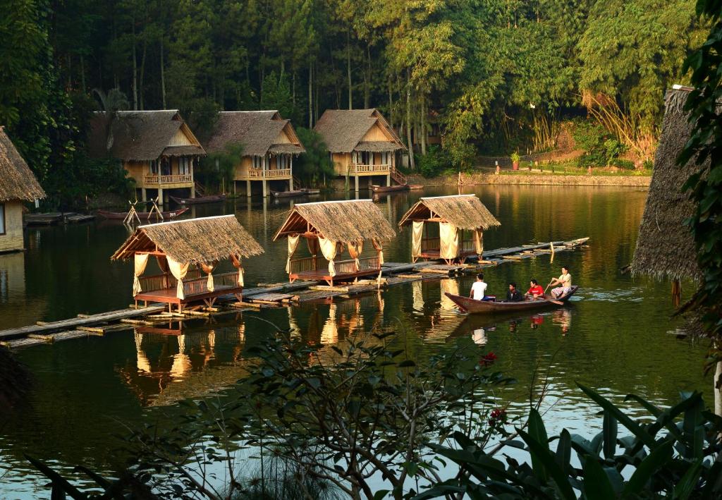 een groep mensen in een boot op een meer met hutten bij Kampung Sampireun Resort & Spa in Garut