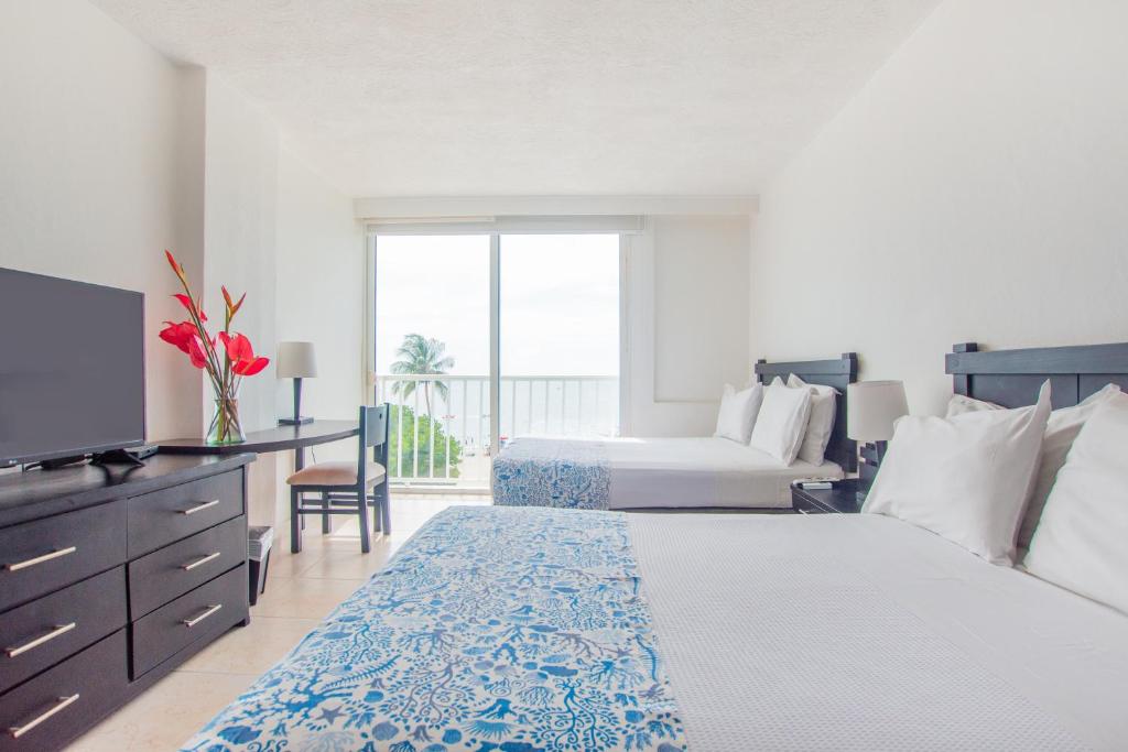 a hotel room with two beds and a television at Tamaca Beach Resort in Santa Marta