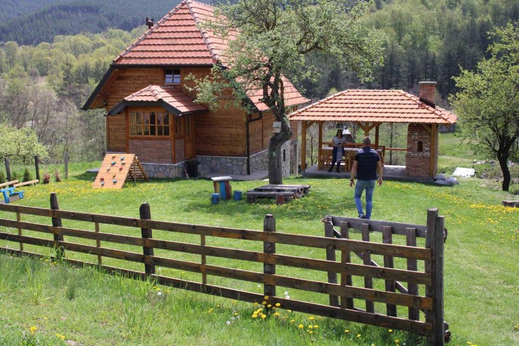 a man walking in front of a wooden cabin at Kuca Karajic in Užice