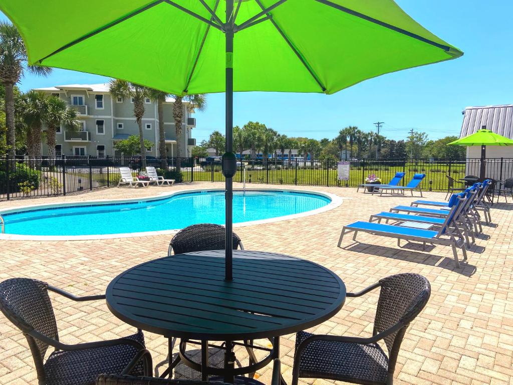 a table with a green umbrella next to a pool at 30-A Inn & Suites in Santa Rosa Beach