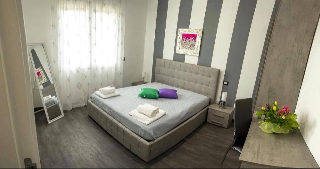 een slaapkamer met een bed met paarse en groene kussens bij A Tre Piani Sul Mare in Campomarino
