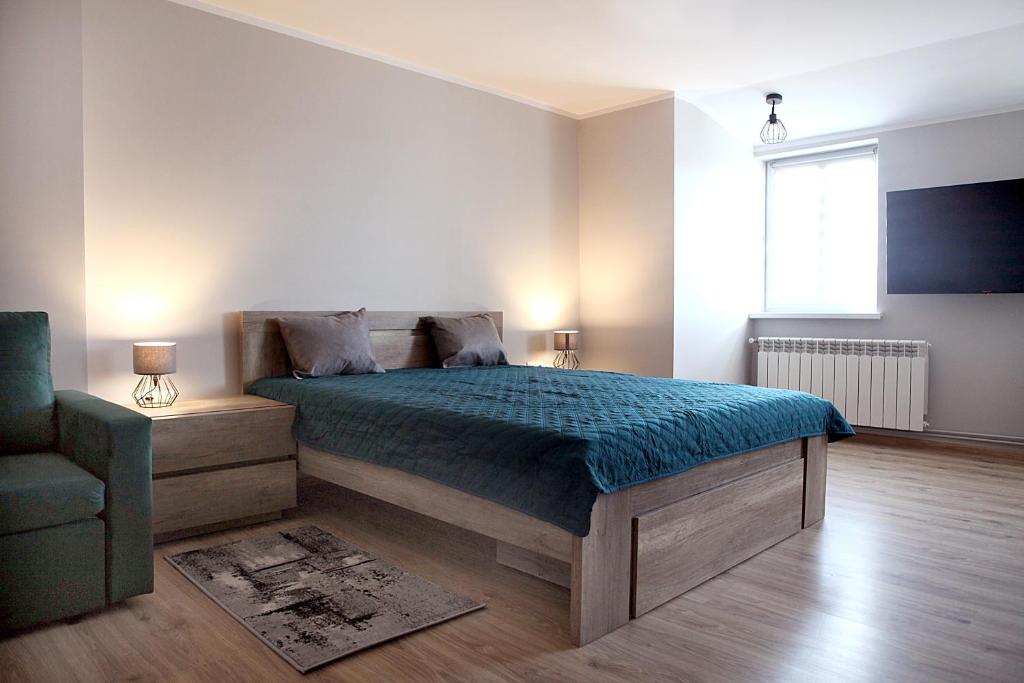 a bedroom with a bed and a chair and a television at NA PODDASZU in Chełmża