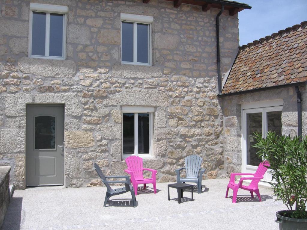 grupa krzeseł siedzących przed kamiennym budynkiem w obiekcie Gîte de Romagers w mieście La Chaze-de-Peyre