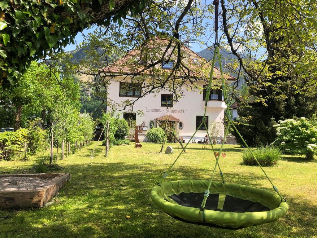 a garden with a swing in front of a house at Ferienwohnung Landhaus zum Sonnenschein in Marquartstein