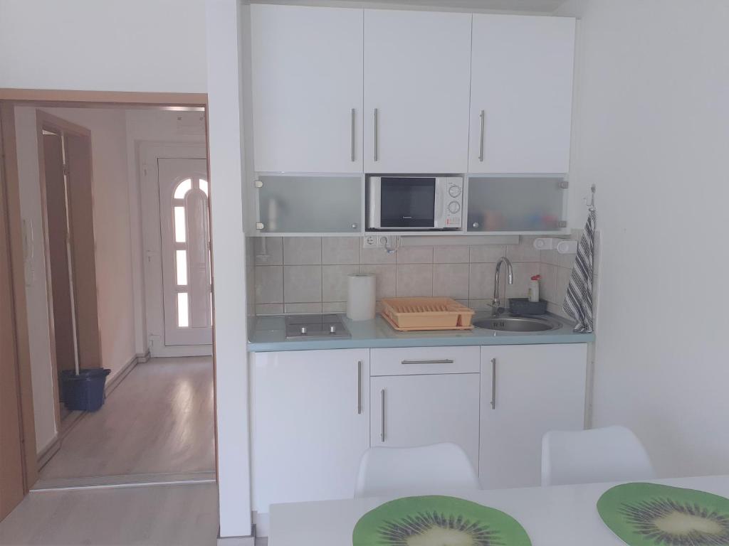 a white kitchen with a sink and a microwave at Liliom apartman in Hévíz