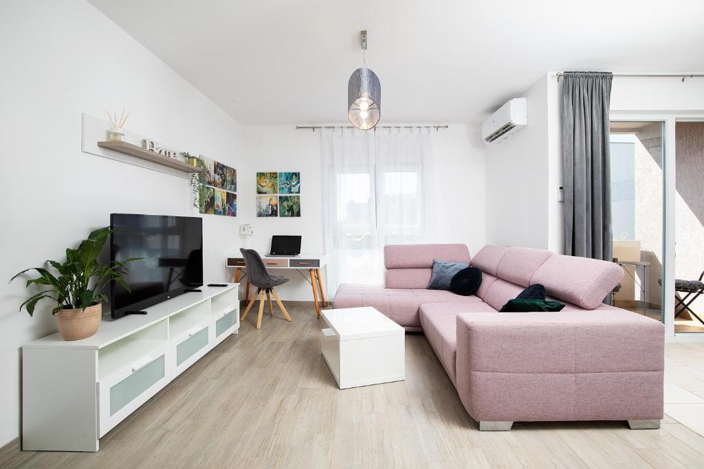 sala de estar con sofá rosa y TV en Sweet City Center with balcony & private Parking en Pula