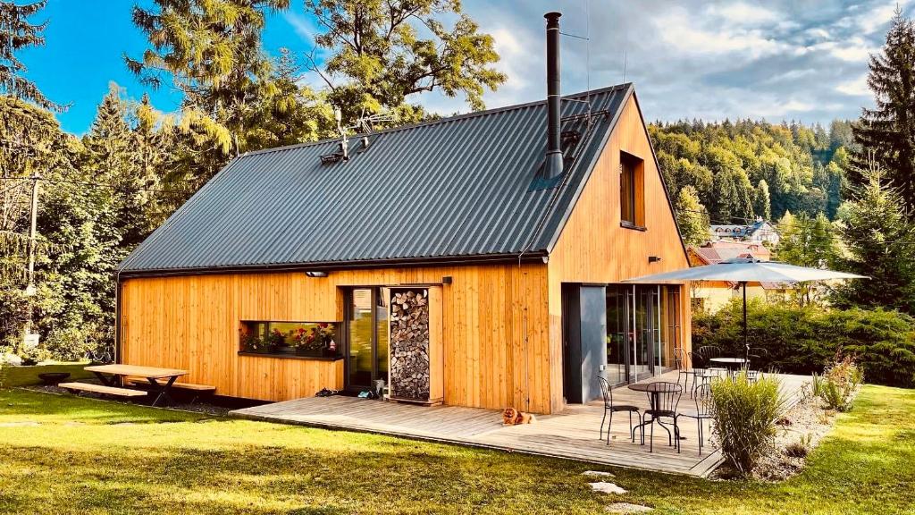 a wooden house with a deck and a table at Chalet Bedřichov in Bedřichov