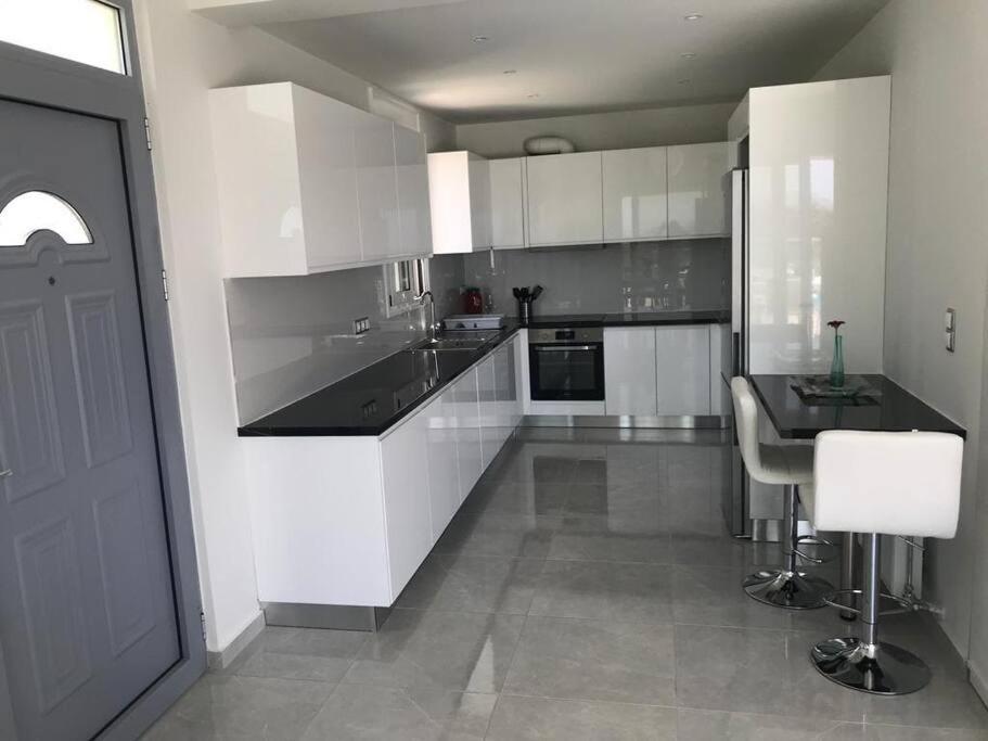 een keuken met witte kasten en een zwart aanrechtblad bij Villa Panorama Modi, with pool and stunning views in Chania