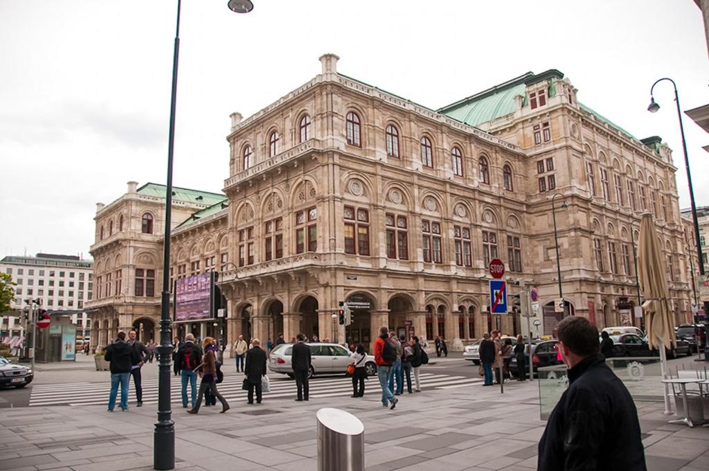 un grupo de personas caminando frente a un gran edificio en OPERA Am Operneck SELF CHECK IN, en Viena