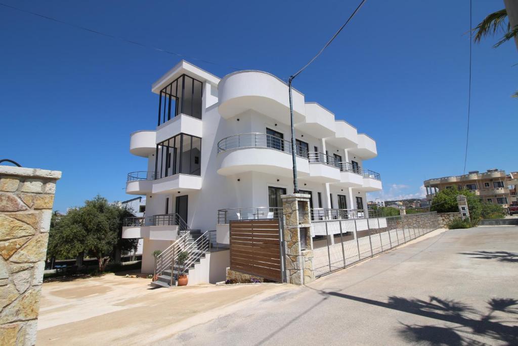 un edificio blanco con ventanas negras en una calle en J&B Hotel en Ksamil