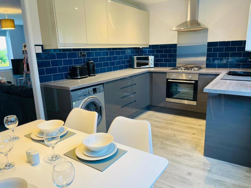 a kitchen with a table and chairs and a kitchen with blue tiles at Newly refurbished 3 bedroom house in Heysham