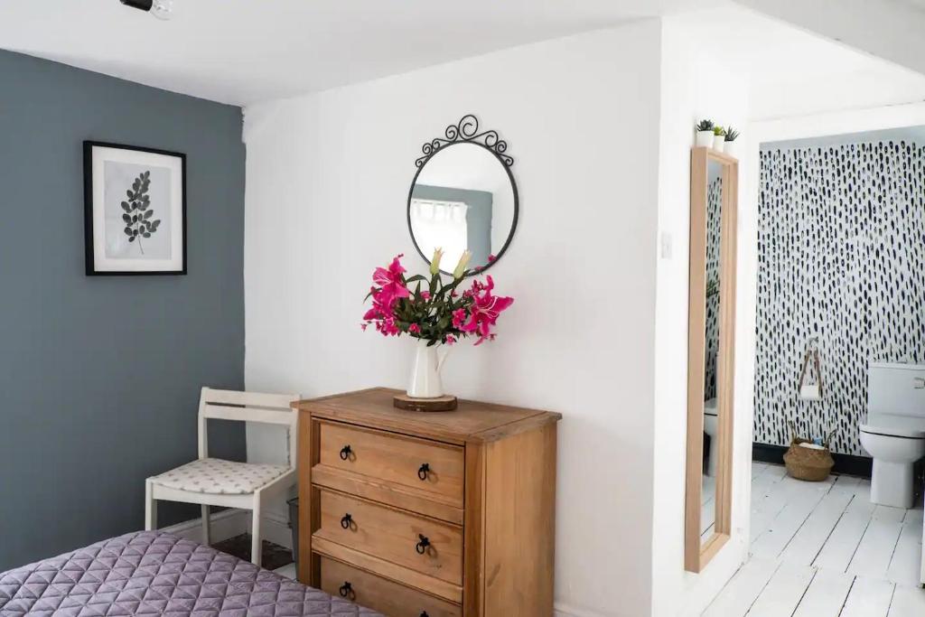 a bedroom with a dresser with a mirror and flowers at Cute Self Catering Flat in the Brecon Beacons in Crickhowell