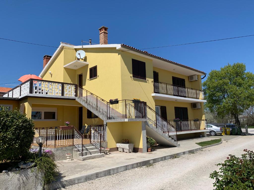 une maison jaune avec un escalier devant elle dans l'établissement Apartment Amalia, à Labin