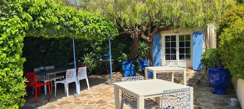 a group of tables and chairs under a tree at Villa Adriandre in Rayol-Canadel-sur-Mer