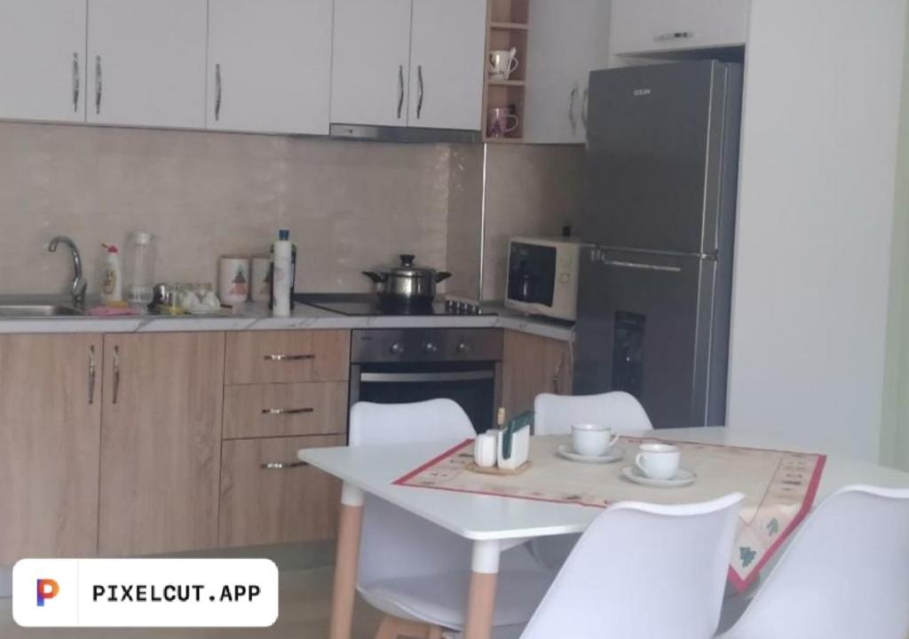 a kitchen with a table and chairs and a refrigerator at Comfort Apartment in Tirana