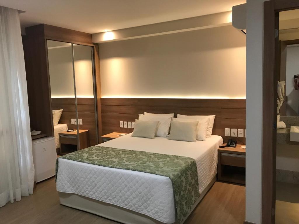 a bedroom with a large bed and a mirror at Condomínio Vista Azul in Aracê