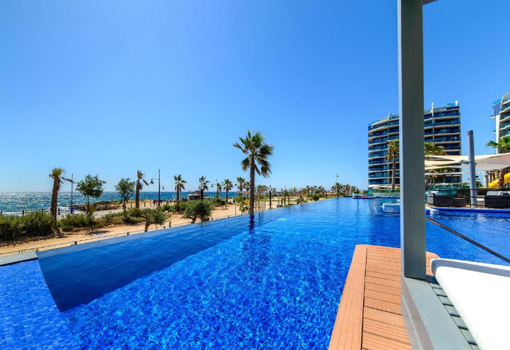 duży basen z palmami i plażą w obiekcie Apartamento Sea Senses, Punta Prima w mieście Torrevieja