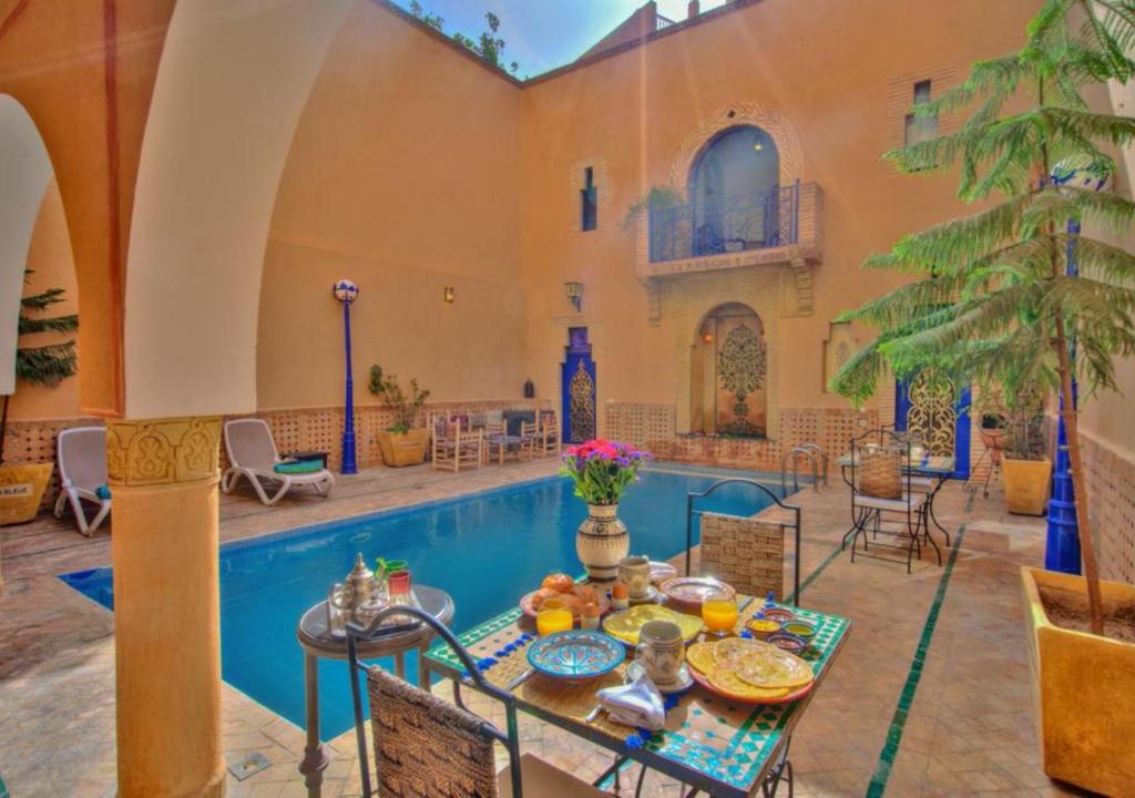 a patio with a table next to a swimming pool at Riad la villa bleue & SPA in Marrakech