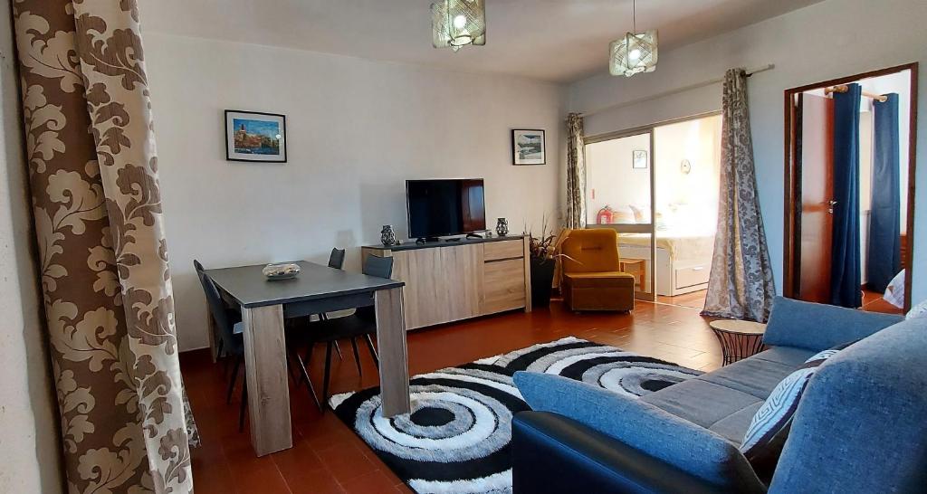 ein Wohnzimmer mit einem blauen Sofa und einem Tisch in der Unterkunft Arrifana View Flat - 3 minutos da Praia in Aljezur