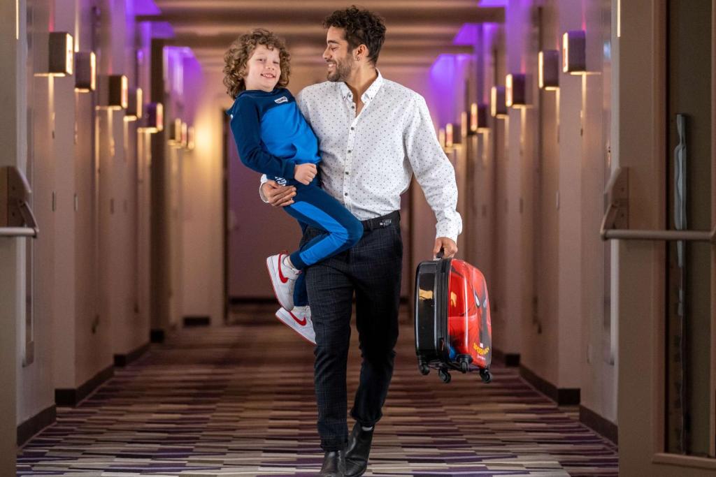 a man walking down a hallway with a child holding a suitcase at YOTEL Istanbul Airport, City Entrance in Istanbul