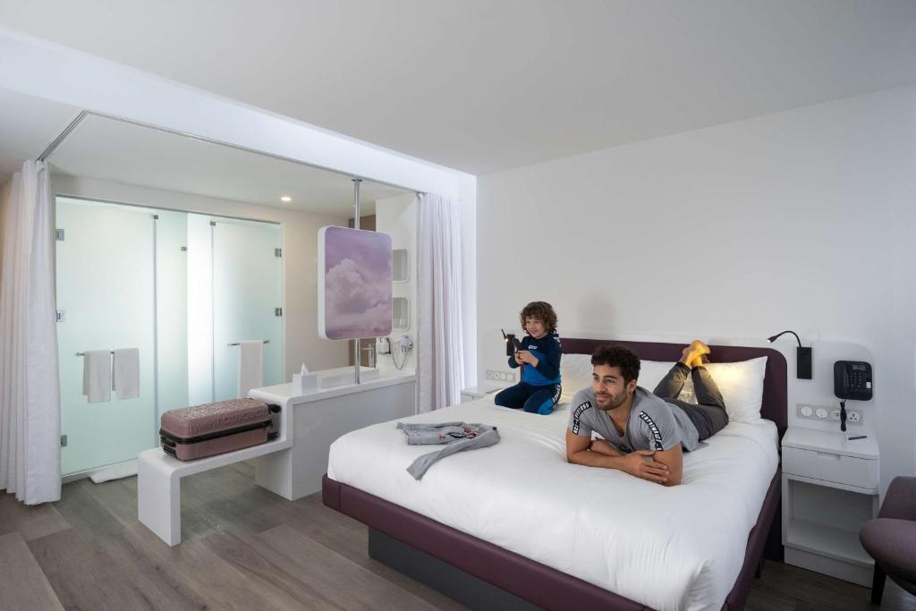 a man laying on a bed with a child on it at YOTEL Istanbul Airport, City Entrance in Istanbul