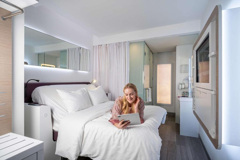 a woman sitting on a bed using a laptop at YOTEL Istanbul Airport, City Entrance in Istanbul