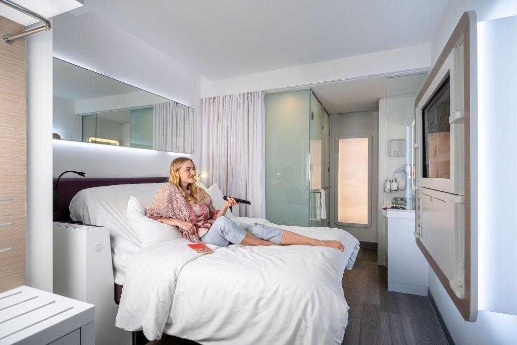 a woman sitting on a bed in a hotel room at YOTEL Istanbul Airport, City Entrance in Istanbul