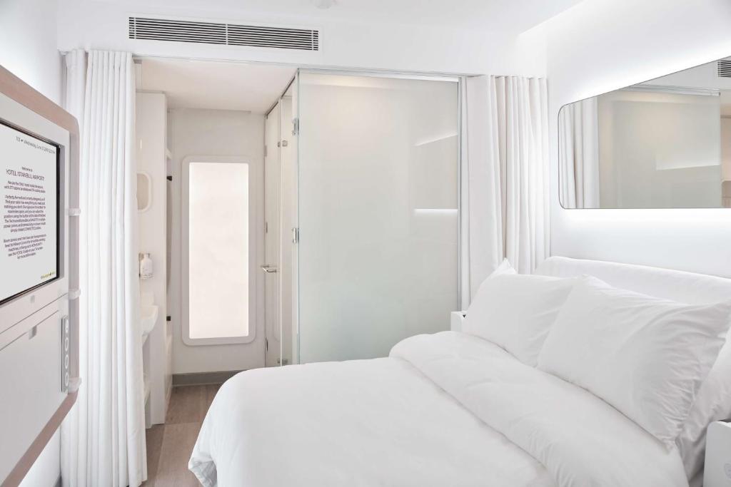 a white bedroom with a white bed and a window at YOTEL Istanbul Airport, City Entrance in Istanbul