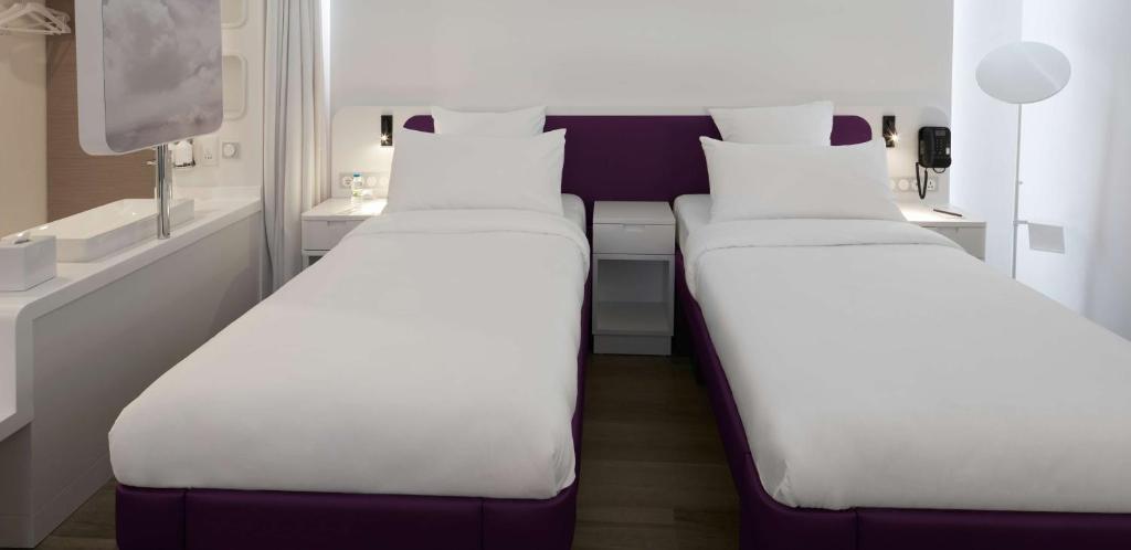 two beds in a room with white and purple at YOTEL Istanbul Airport, City Entrance in Istanbul