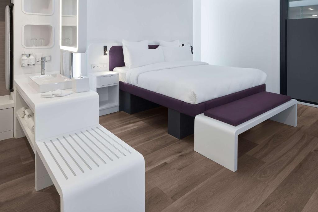 a white bedroom with a bed and a bench at YOTEL Istanbul Airport, City Entrance in Istanbul