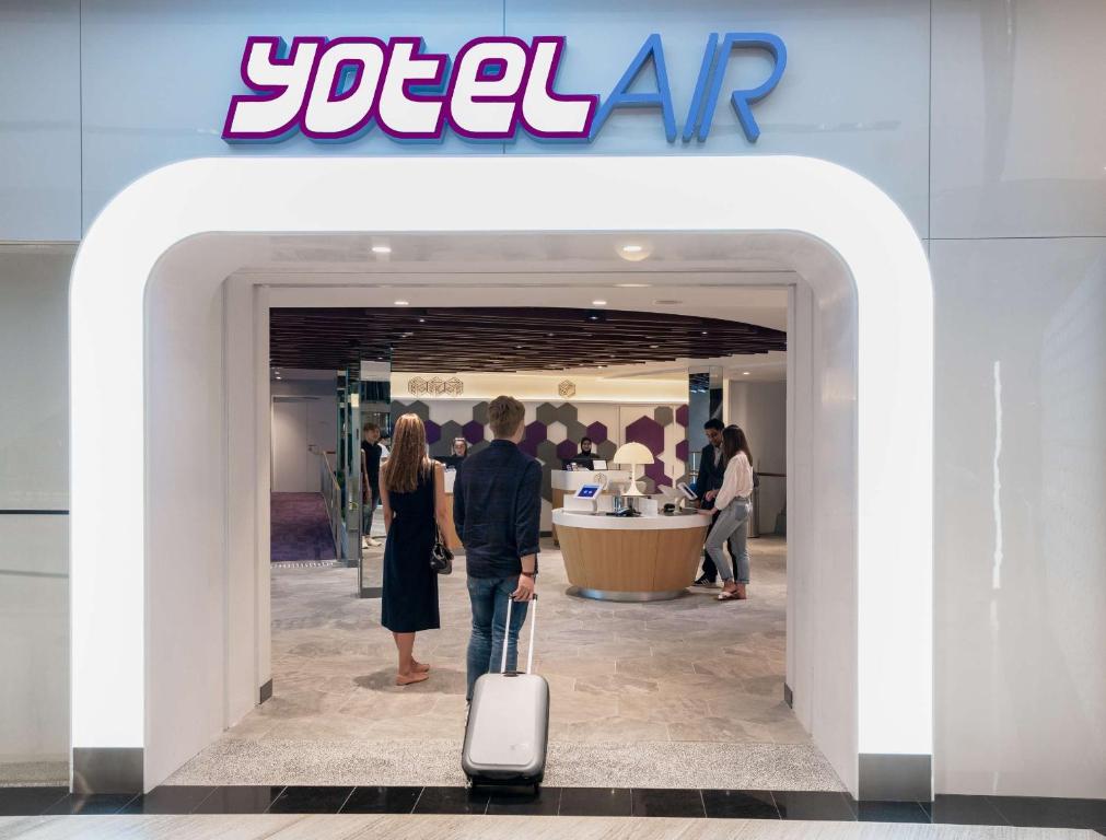 a man and a woman with a suitcase walking into a store at YOTELAIR Singapore Changi Airport Landside in Singapore