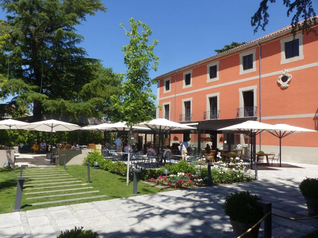 un patio con mesas y sombrillas y un edificio en Sofraga Palacio, World Hotels Crafted, en Ávila