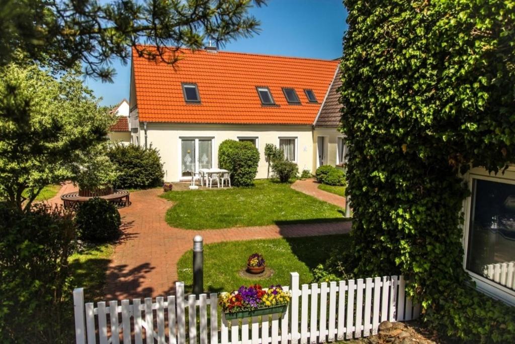 a white fence in front of a house with an orange roof at Haus Strandgang, Whg 4 in Kellenhusen