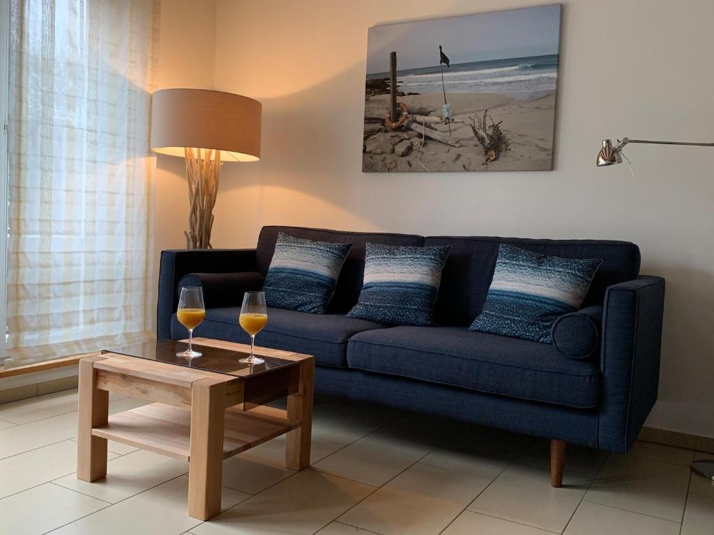 ein Wohnzimmer mit einem blauen Sofa und 2 Gläsern Wein in der Unterkunft Ferienhaus in Heiligendamm mit Sauna & Kamin - [#23967] in Heiligendamm