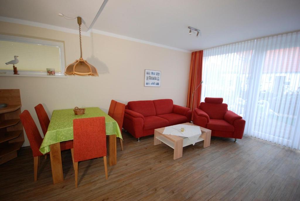 a living room with a red couch and a table at Haus Strandgang, Whg 2 in Kellenhusen