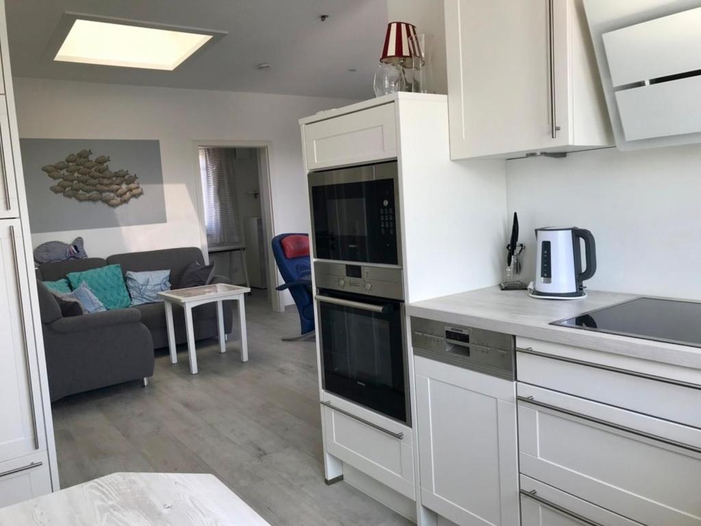 a kitchen with white cabinets and a living room at Penthouse Wohnung Christine Okroy in Kellenhusen