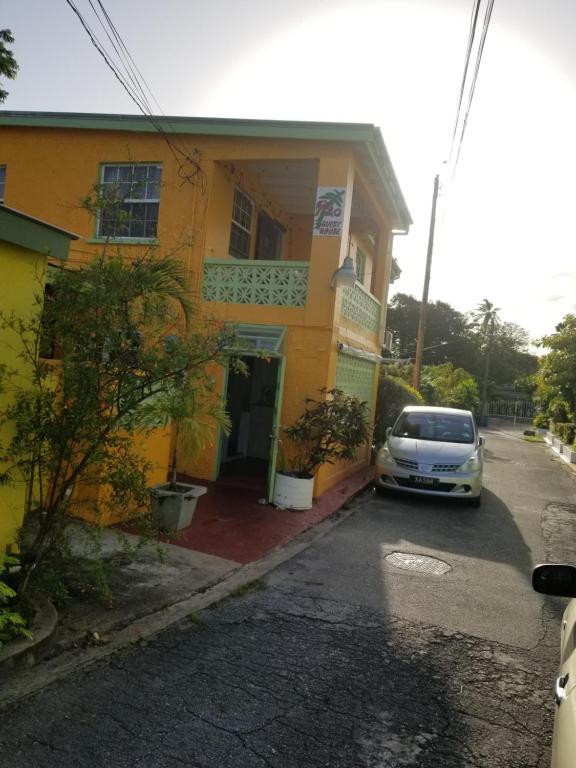 a car parked in front of a yellow house at Rio Guesthouses in Christ Church