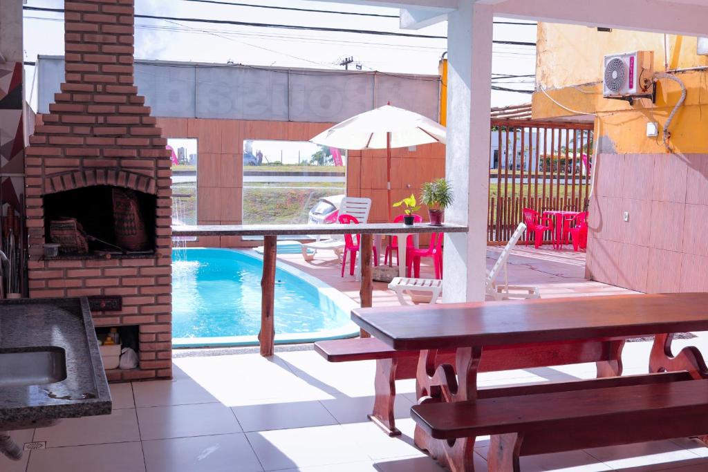 a patio with a pool and a table and a fireplace at Pousada e Restaurante Palomar in Ilhéus