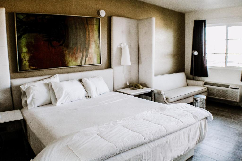 een slaapkamer met een groot wit bed en een stoel bij Devonshire Inn Motel in Rosamond
