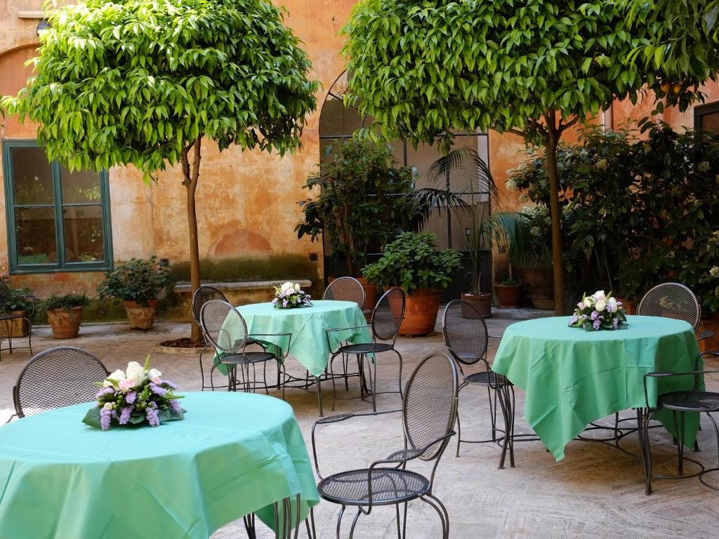 dwa stoły i krzesła z zielonymi obrusami w obiekcie Casa Di Santa Francesca Romana a Ponte Rotto w Rzymie