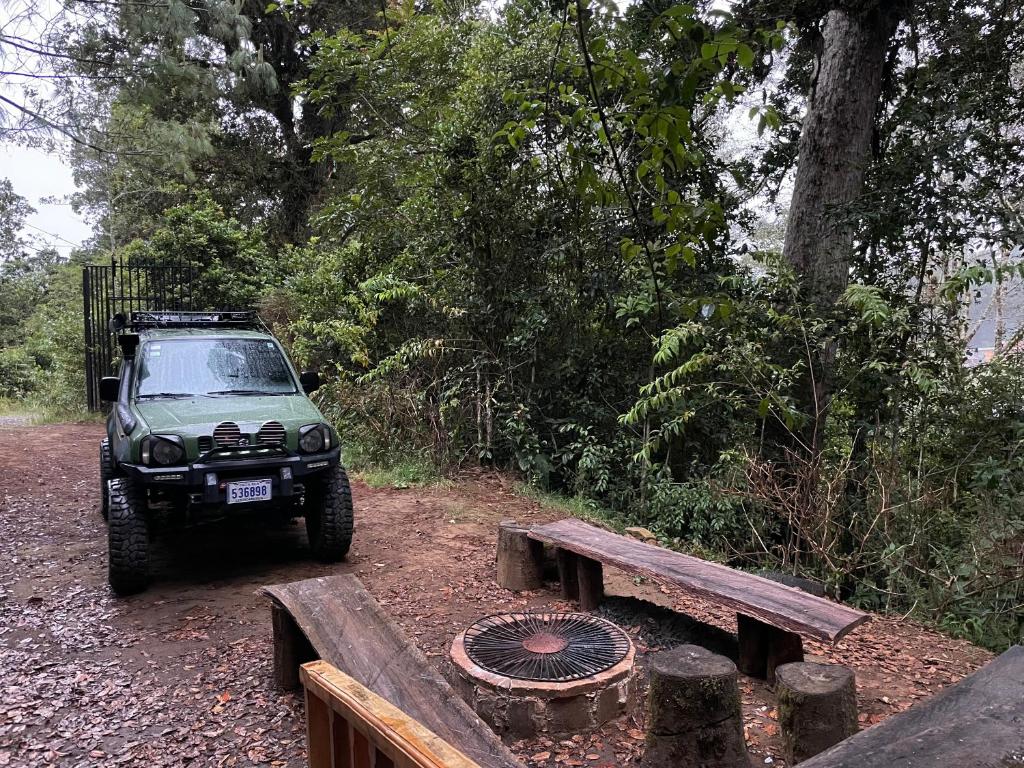 a jeep parked next to a bench and a grill at La Bromelia/Cabaña de Montaña, Cerro de la Muerte. in Cartago