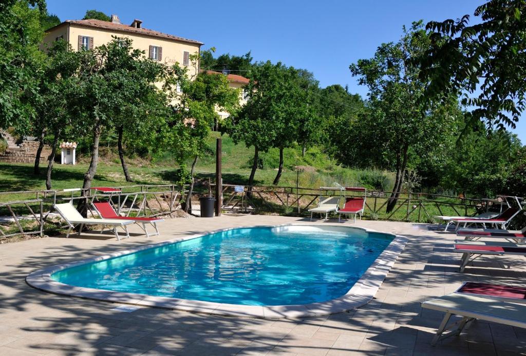 une piscine avec des chaises et une maison en arrière-plan dans l'établissement Casa Tartufo, à Sassoferrato