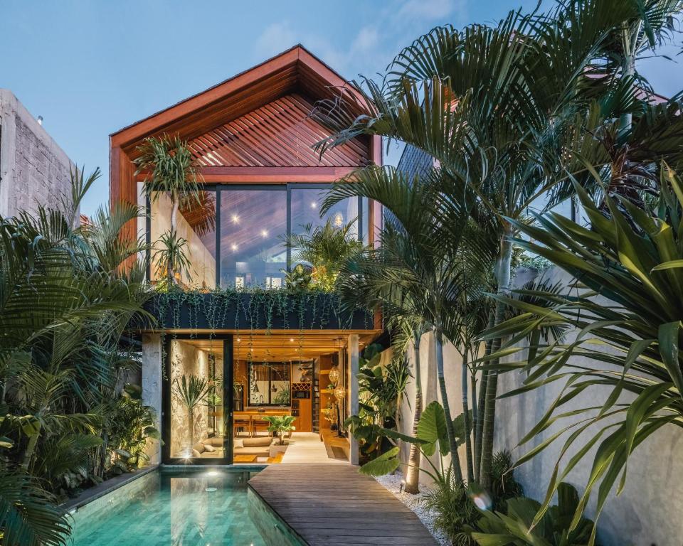 een huis met een zwembad en palmbomen bij Black Sand Villas in Canggu