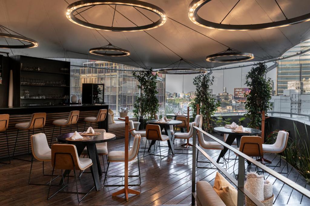un restaurante con mesas, sillas y ventanas grandes en Suites Contempo, en Ciudad de México
