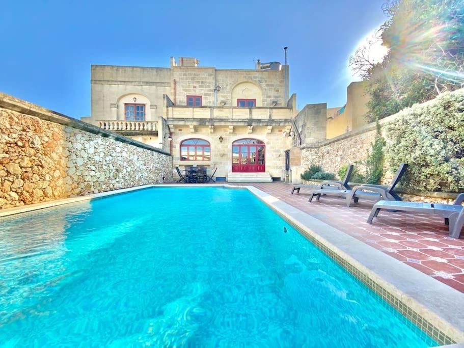 una piscina frente a una casa con un edificio en Villa Rossa Gozo - 5 bedroom ensuite with pool & jacuzzi, en Xewkija