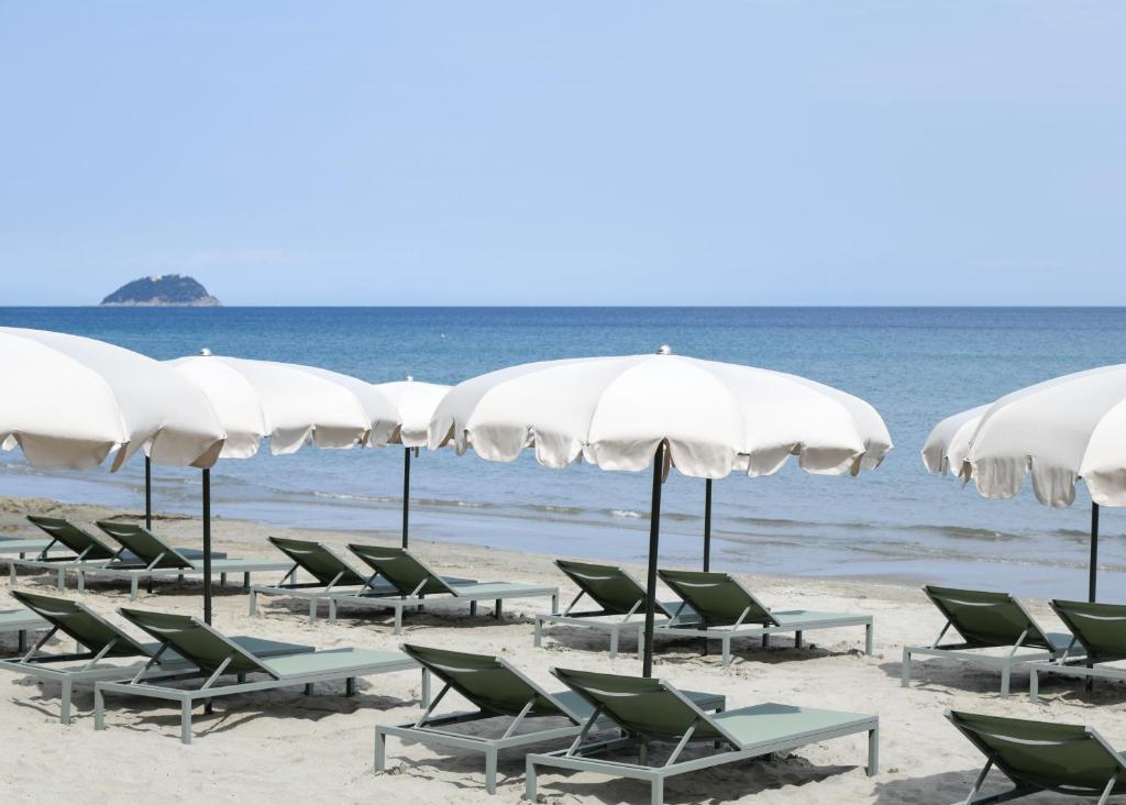 a group of chairs and umbrellas on a beach at Hotel Windsor in Laigueglia